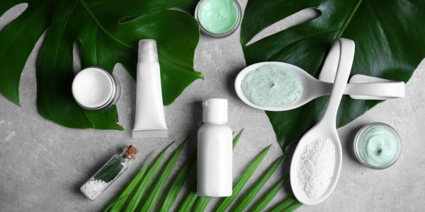 Natural cosmetics and leaves on grey background